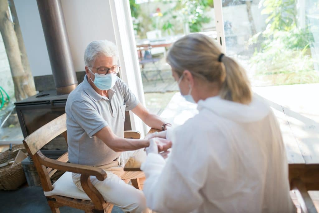 Doctor performing checkup on senior man at home