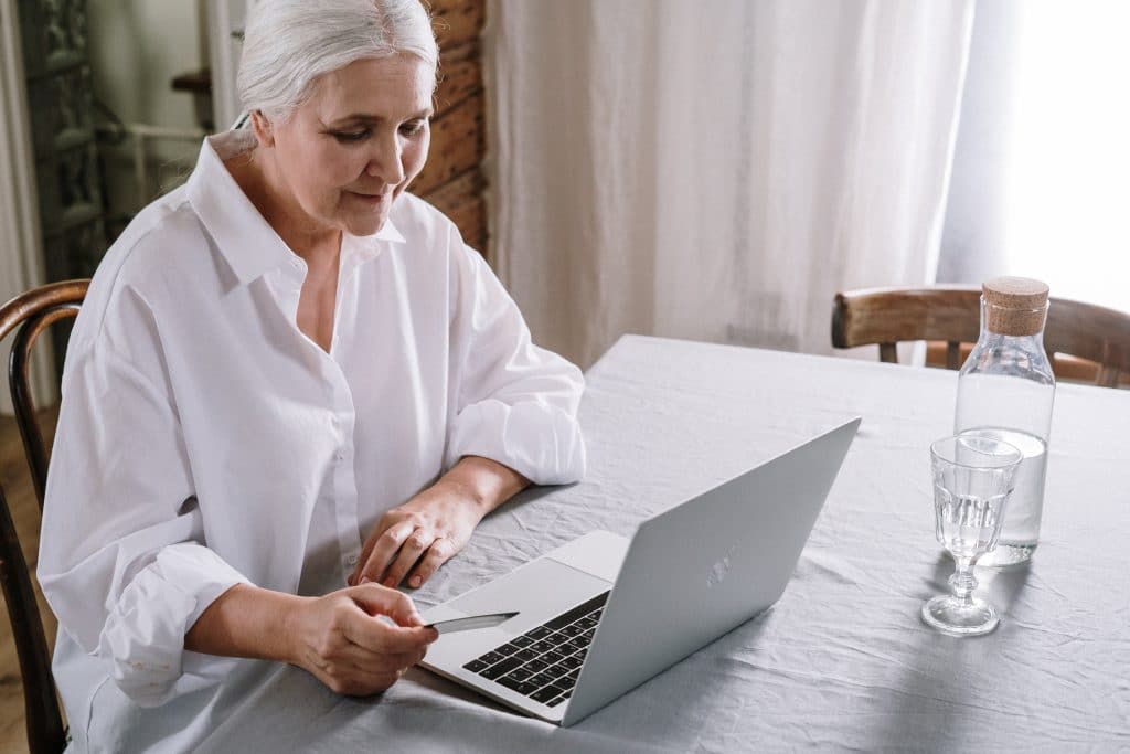 older woman holding credit card while on laptop