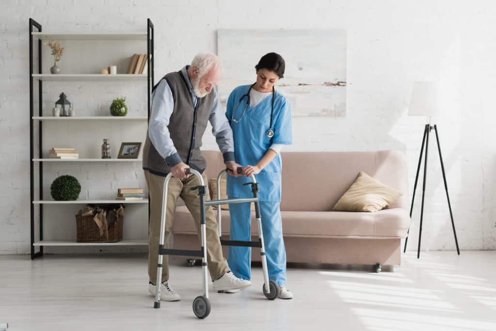 A nurse helping a man get around his home.